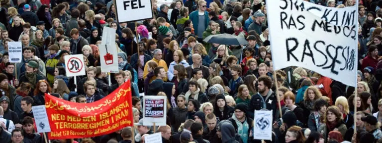 Protest crowd with banners and signs advocating against racism and violence at Barnard Center for Research on Women.