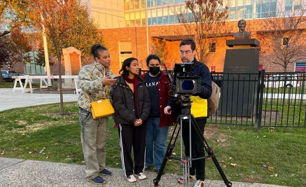 An outdoor scene featuring women discussing a project in front of Barnard Center for Research on Women, capturing a collaborative moment.