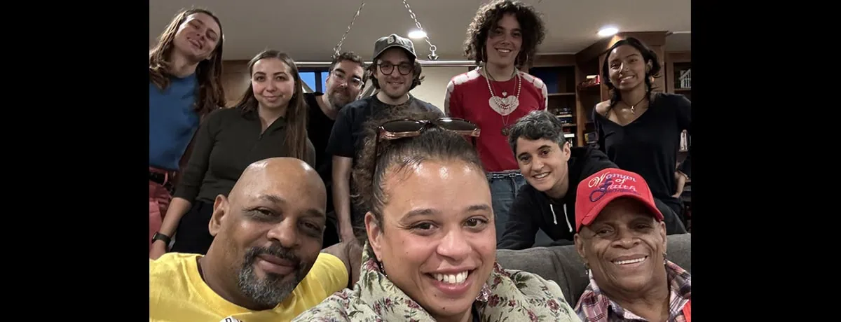 Diverse group of women and men pose together for a photo in a cozy indoor space.