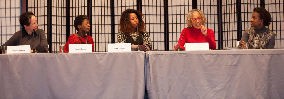 The 5 panelists for the Sustaining Harlem panel seated on stage at a grey table.