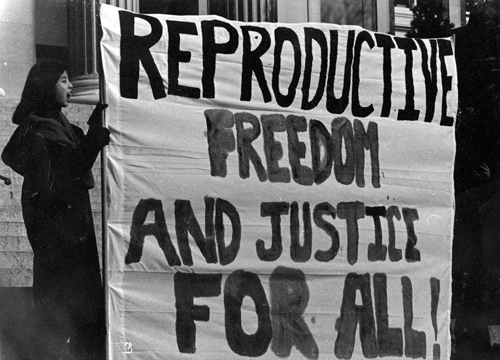 Protestors holding sign reading "Reproductive Freedom and Justice for All" circa 1990s
