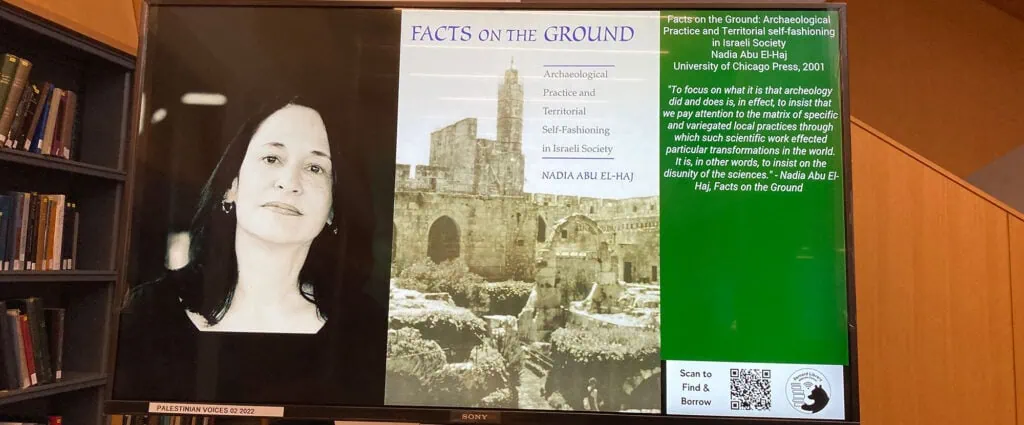 Alt: Photo of a display board promoting Nadia Abu El-Haj’s book “Facts on the Ground” with her photo and book cover.