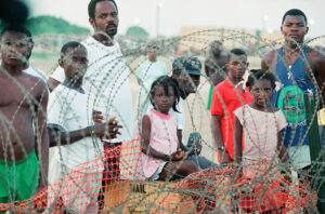 Young Haitian refugees look out across barbed wire to other camps holding Haitians at the Guantanamo Naval Base in Cuba, Sept. 7, 1994. There are over 14,000 Haitian refugees in Guantanamo. The Washington Post reported on Friday, that Haitian exiles held at Guantanamo Bay are being recruited for the interim force that would be installed almost immediately after an invasion. (AP Photo/Doug Mills)